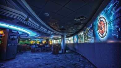 Analysts monitoring rows of screens inside a dark cyber security operations centre at night.